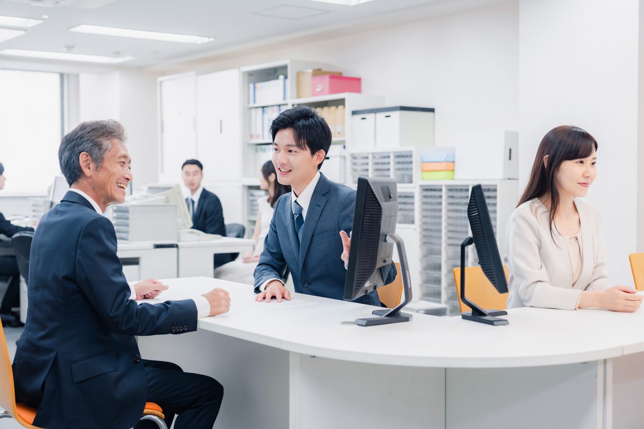 明るい窓口で職員と来訪者が向かい合って相談している様子(イメージ)